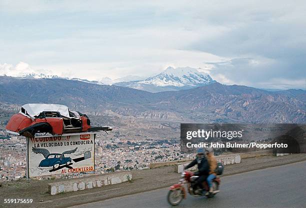 Road safety sign above the city of La Paz in Bolivia, circa 1983. It reads 'Cuidado! La Velocidad lo conducira al Cementerio' .