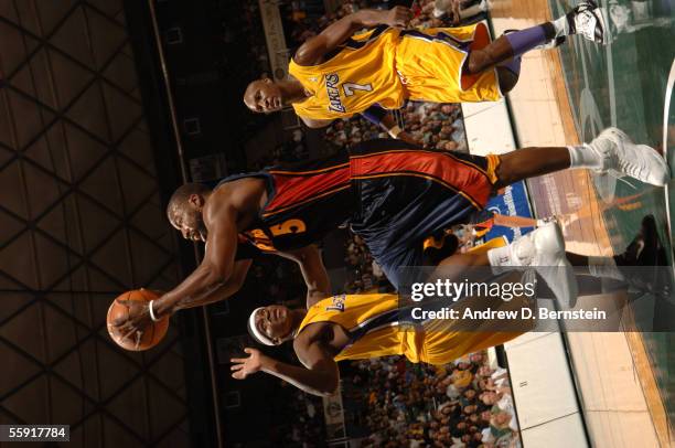 Baron Davis of the Golden State Warriors drives for a shot attempt against Smush Parker and Lamar Odom of the Los Angeles Lakers during a preseason...