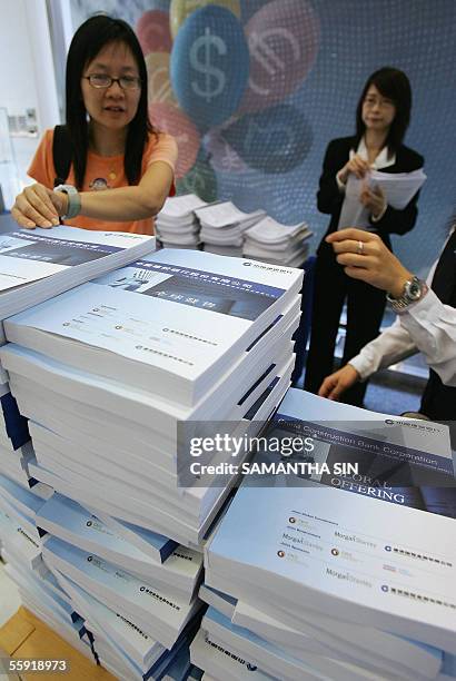 Bank staff distribute copies of the prospectus for the Initial Public Offering of China Construction Bank in Hong Kong, 14 October 2005. The CCB is...