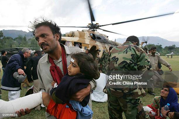 Resident prepares to carry an injured young girl onto a rescue helicopter on October 13, 2005 in Muzaffarabad, capital city of Pakistan-controlled...