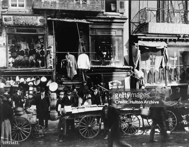 Shoppers congregate as vendors sell their wares on the sidewalk outside of haberdasheries at 57 Hester Street and 55 Hester Street on the Lower East...