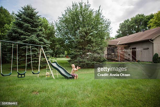 little boy on slide getting sprayed - annie sprinkle stock pictures, royalty-free photos & images