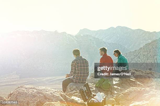 three friends sitting on mountain top - high key foto e immagini stock