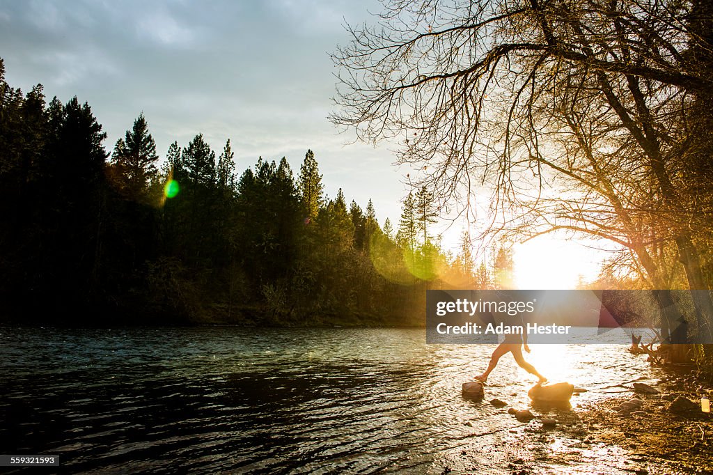 A man jumping across two rocks on a river