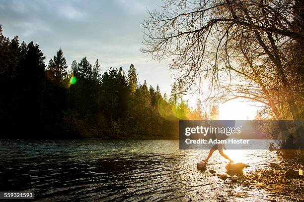 a man jumping across two rocks on a river - mendocino county stock pictures, royalty-free photos & images