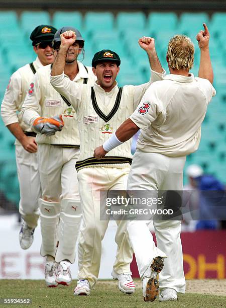 Australian bowler Shane Warne celebrates with teammates after taking the wicket of World XI batsman Rahul Dravid of India, caught Matthew Hayden for...
