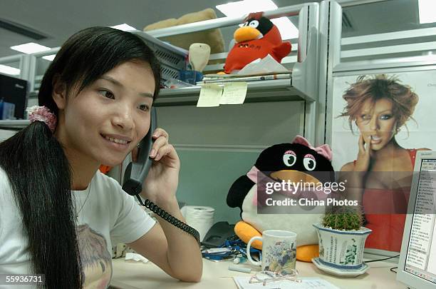 Worker makes a phone call beside an emblem of Tencent QQ instant messaging service, in the headquarters office of the Tencent Holdings Limited on...