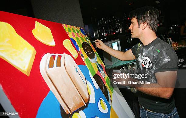 Actor and artist Thom Bierdz paints a piece of art to be put up for bid during the launch of the "uBid for Hurricane Relief" charity auction and...