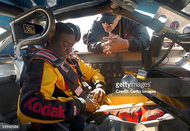 Joe Hernderson lll, buckles himself into a late-model race car, while driver mentor Wendell Scott, Jr. Gives him some pointers before his try-outs...