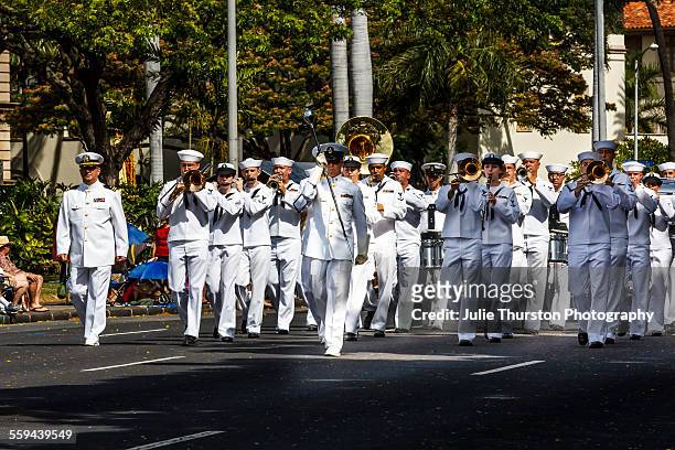 Navy Pacific Fleet Band wearing white military uniforms, marching and playing brass instruments in the annual downtown King Kamehameha Day Parade in...