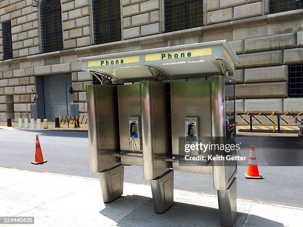 Two open phone booths side-by-side on a sidewalk, across from the Federal Reserve Bank of New York Building in Manhattan, NYC - May 28, 2015