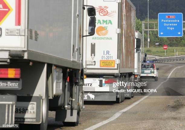 Guardia Civil patrol car escorts lorries during the mass transport strike by road hauliers in Tui, near the Portuguese border, 18 October 2005. The...