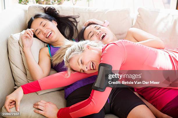 group of women collapsing on sofa after exercise - after run photos et images de collection