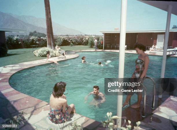 Female and male guests relax near and swim in the piano-shaped swimming pool at Twin Palms, the estate belonging to American singer and actor Frank...