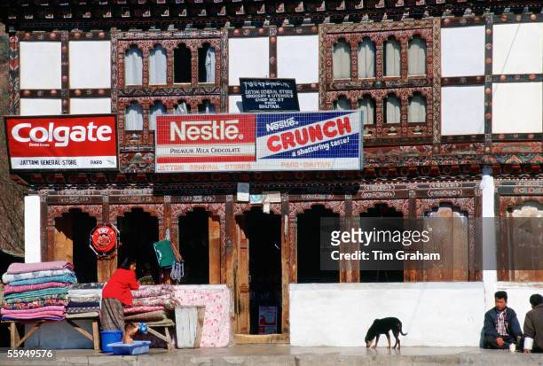Woman at work, child playing in bath, men and dog in front of shop, Paro, Bhutan.