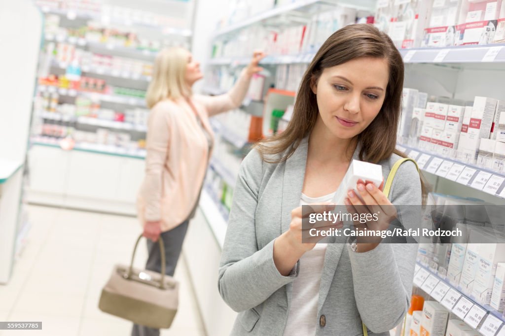 Customer reading label on box in pharmacy