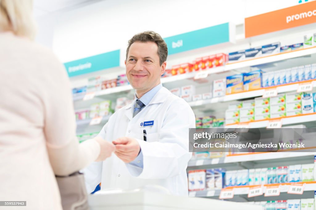 Smiling pharmacist assisting customer in pharmacy