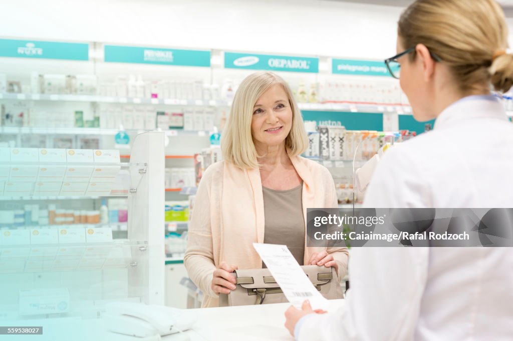 Customer giving prescription to pharmacist in pharmacy