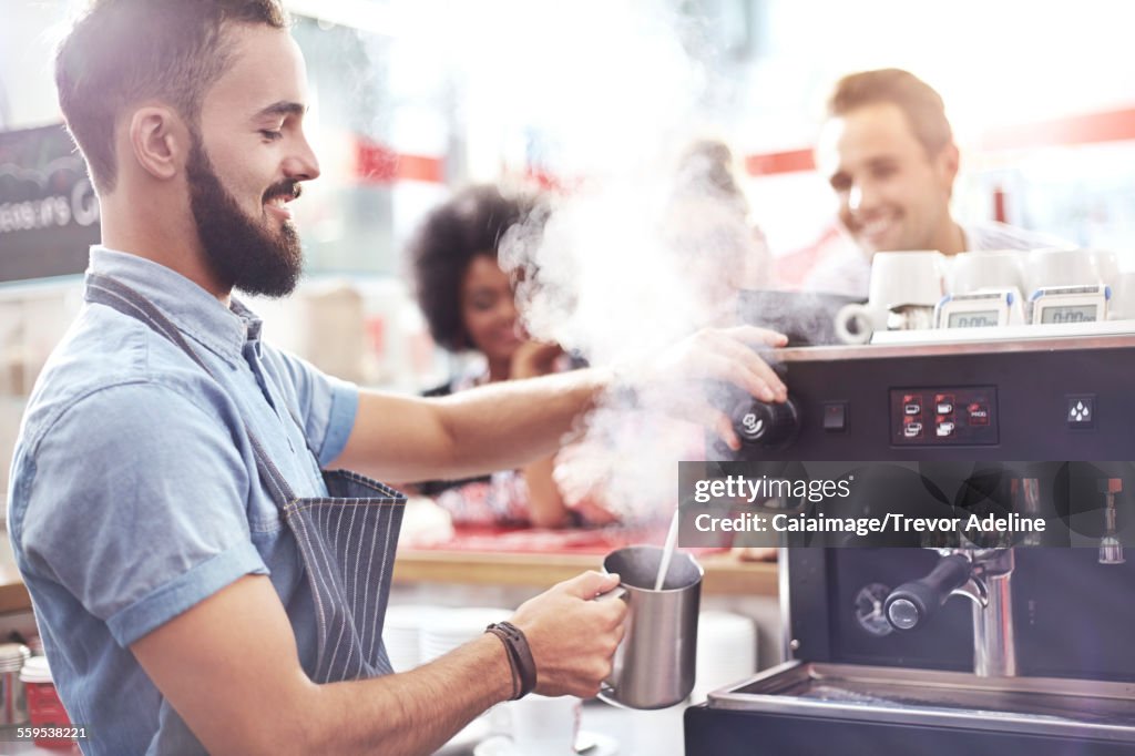 Barista steaming milk in cafe