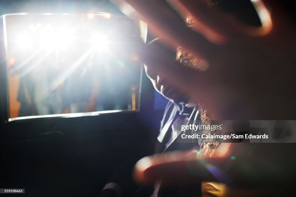 Celebrity couple blocking camera in limousine at event