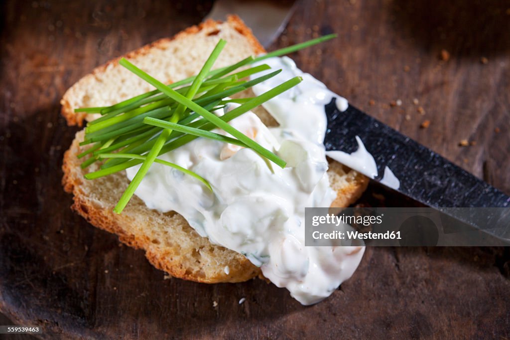 Slice of potato bread spread with herbed curd cheese garnished with chives