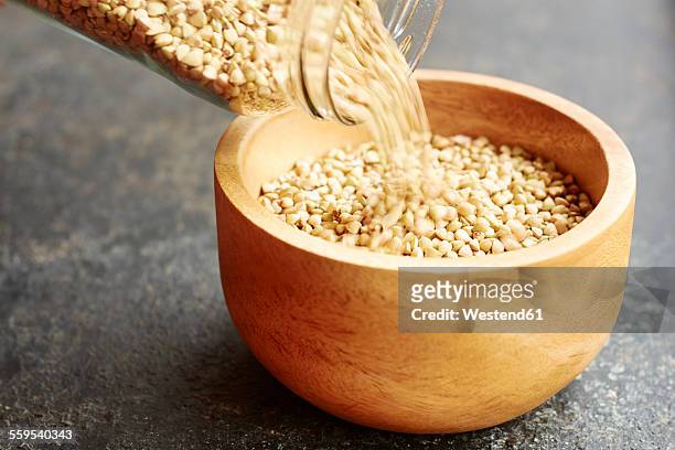 hemp seeds being poured into a wooden bowl - hemp seed fotografías e imágenes de stock