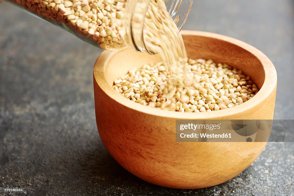 Hemp seeds being poured into a wooden bowl