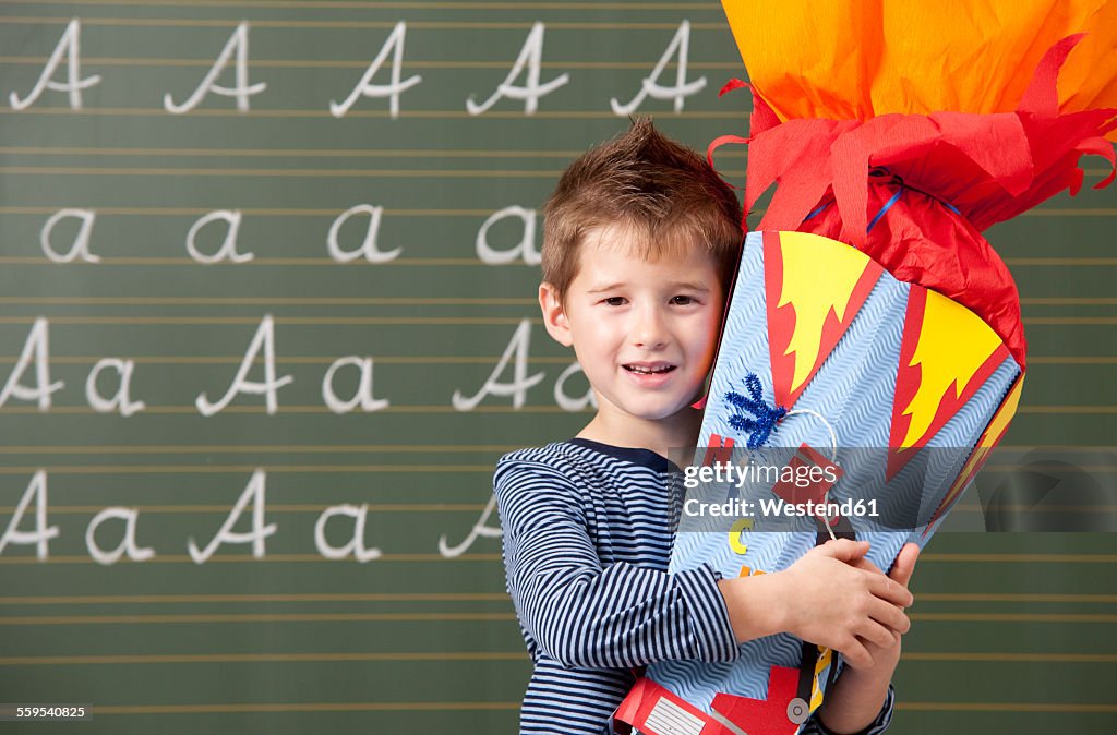 Happy boy with school cone at blackboard
