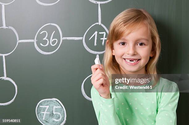 smiling schoolgirl at blackboard with arithmetic problem - portrait of a young girl with gappy teeth and blond hair stock pictures, royalty-free photos & images