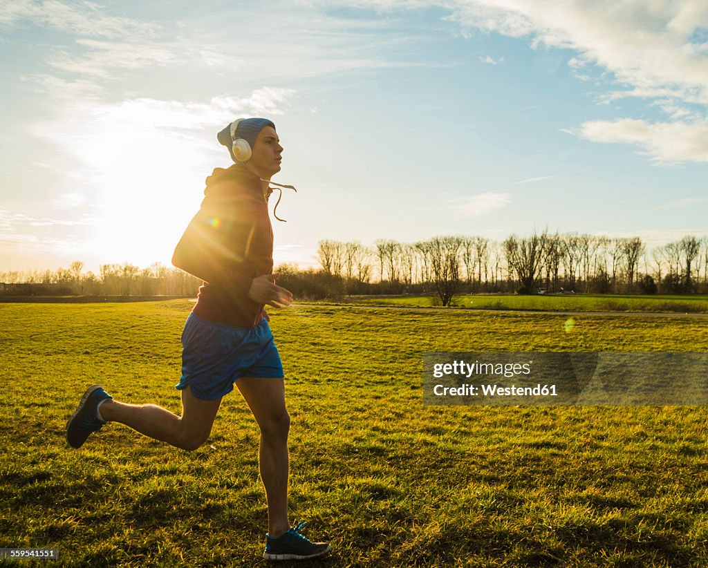 Germany, Mannheim, young man jogging in meadow