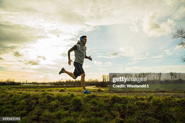 germany, mannheim, young man jogging - beeldtechniek stockfoto's en -beelden