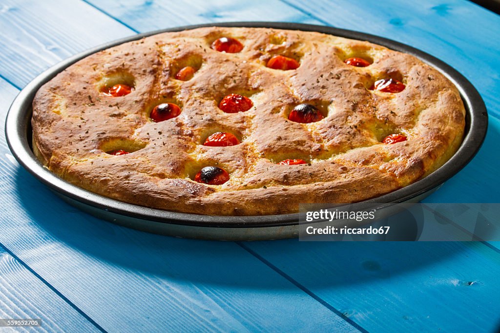 Pizza Made With Tomatoes And Oregano On Blue Table
