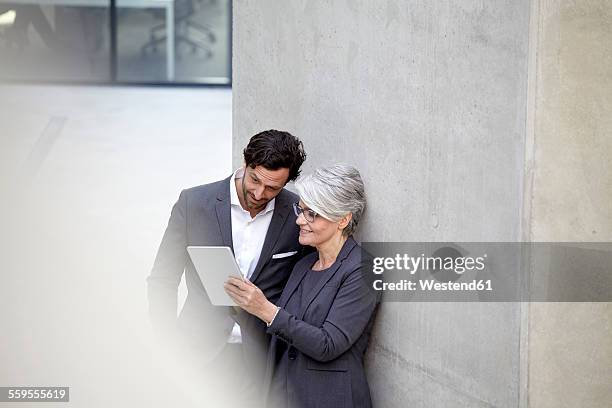 two business people with digital tablet in modern architecture - mann schlicht stock-fotos und bilder