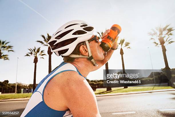 spain, mallorca, sa coma, portrait of triathlet drinking water on bicycle - drink driving stockfoto's en -beelden