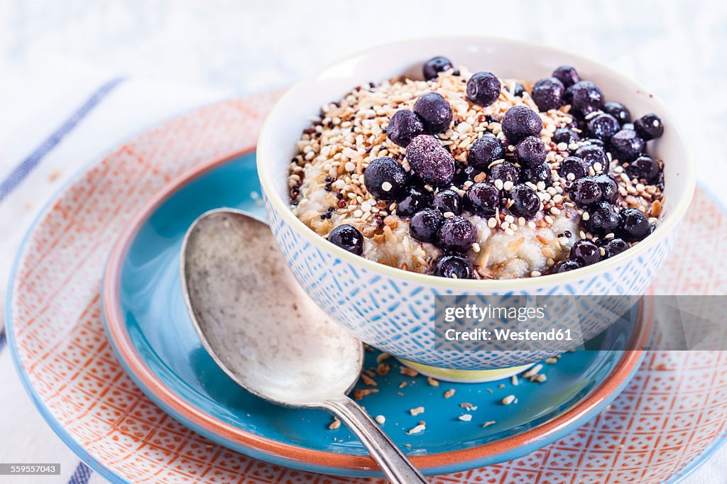 Vegan superfood breakfast with porridge, almond milk, blueberries and roasted quinoa