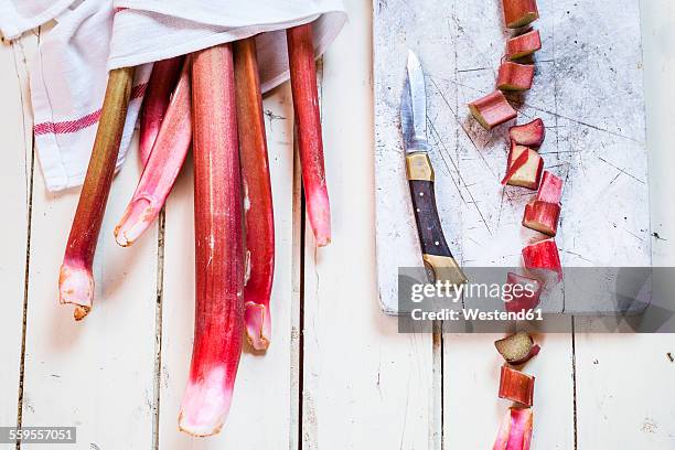 rhubarb stalks, cut in pieces, board and knife - rabarber stockfoto's en -beelden