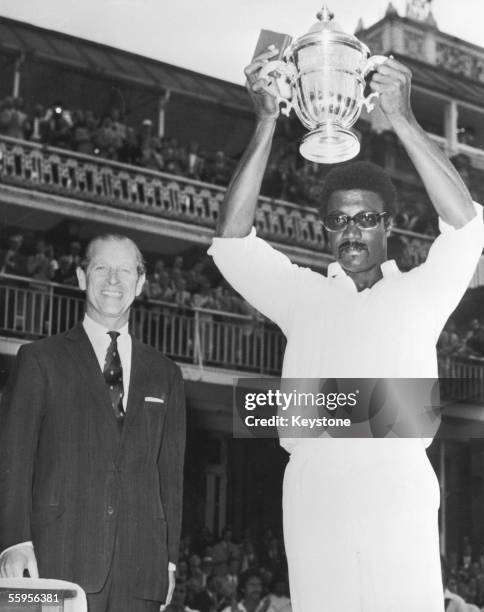 President Prince Philip, Duke of Edinburgh looks on as West Indies captain Clive Lloyd raises the trophy after his team won the final of the...