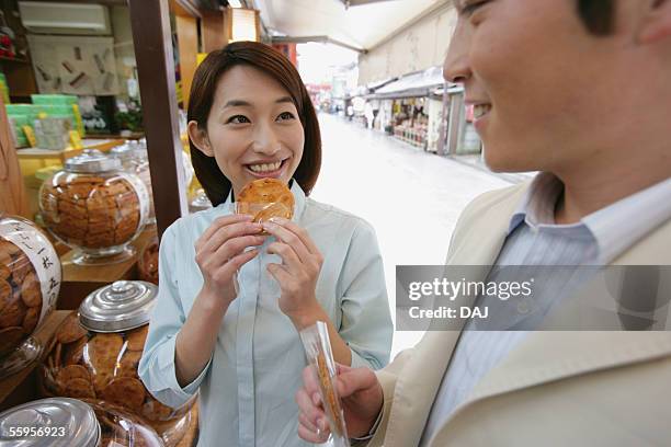 young couple eating japanese snack, senbei, tokyo, japan - senbei stock pictures, royalty-free photos & images