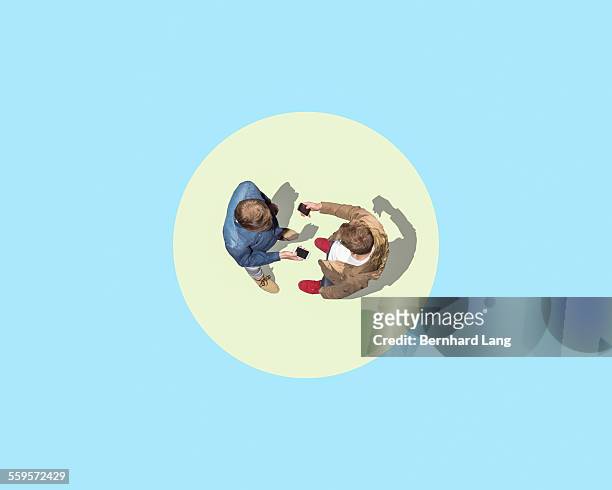 two men facing with mobile phones, aerial views - contact color background photos et images de collection
