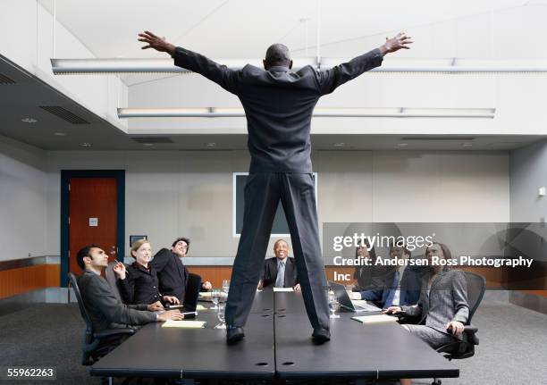 businessman standing on conference table - schocktaktik stock-fotos und bilder