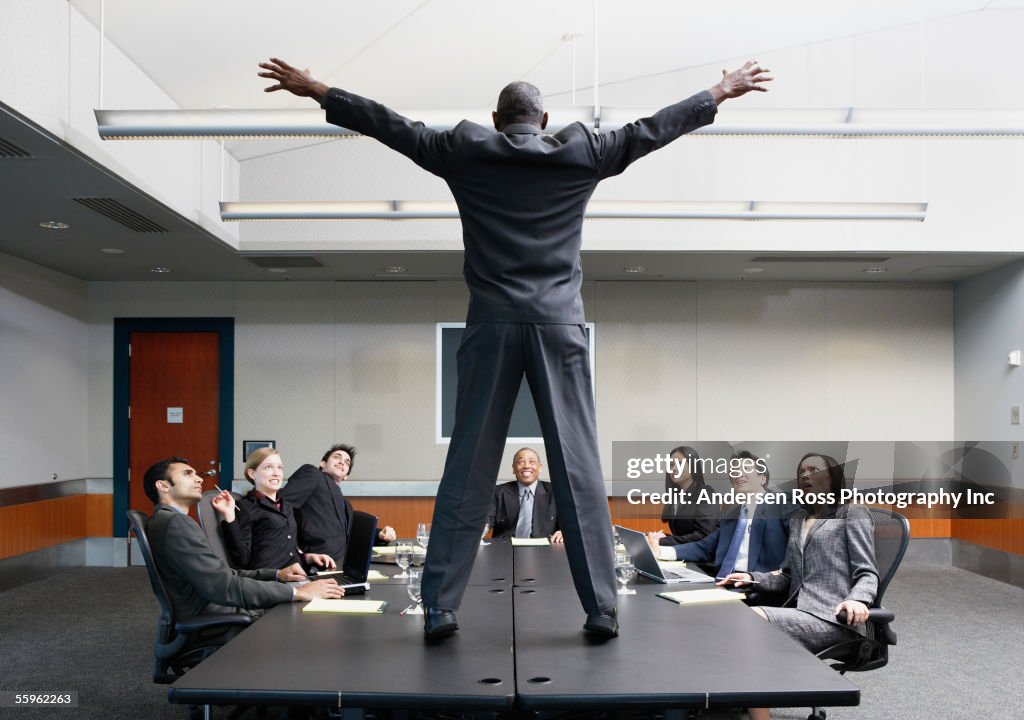 Businessman standing on conference table