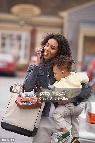 mother carrying child talking on mobile phone - busy toddlers stock pictures, royalty-free photos & images