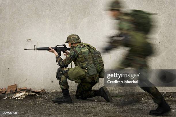 side profile of a soldier aiming his rifle - military rucksack stock pictures, royalty-free photos & images