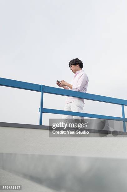 businessmen using smart phone on the roo - railings ストックフォトと画像