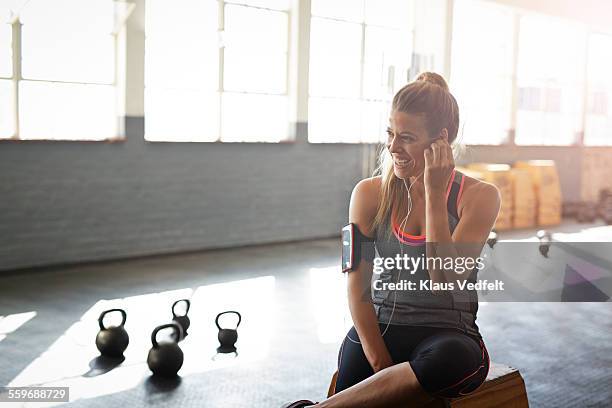 woman putting headphones in ear at gym gym - south africa training stock pictures, royalty-free photos & images