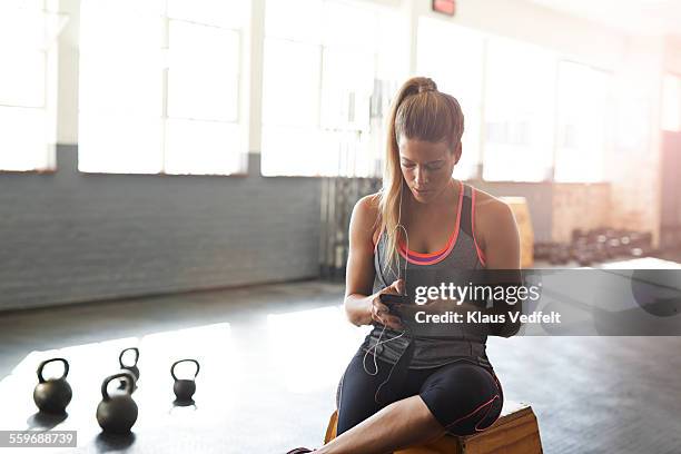 woman tjecking results on smartphone at gym - results gym stock-fotos und bilder
