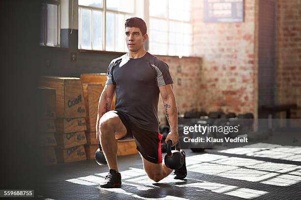 gym instructer doing lunges with kettlebells - sporttraining stock-fotos und bilder