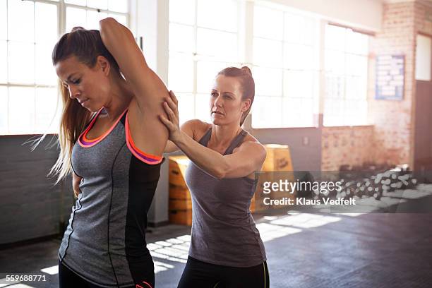 woman assisting friend with stretch after training - personlig tränare bildbanksfoton och bilder