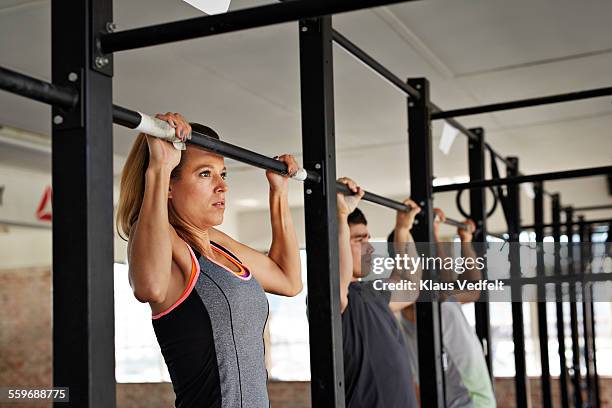 woman & 2 men doing pull-up's at gym gym - doing pull ups stock pictures, royalty-free photos & images