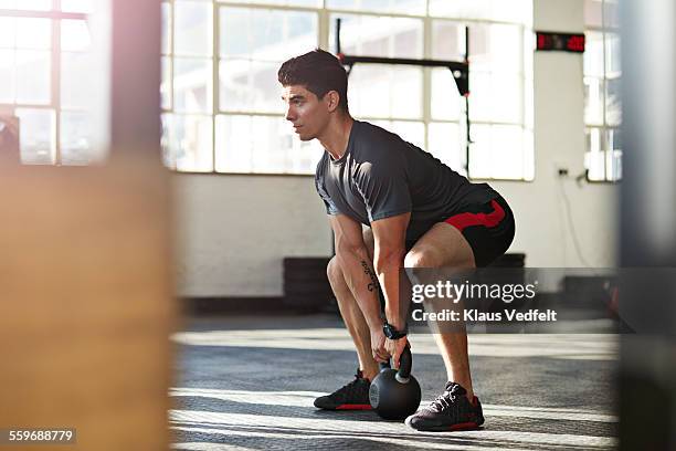 gym instructor lifting kettlebell at urban gy - hombre agachado fotografías e imágenes de stock